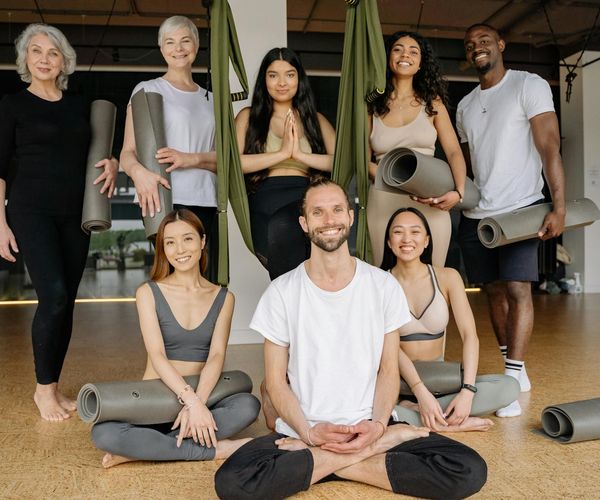 Diverse group of people smiling and preparing for a yoga class.